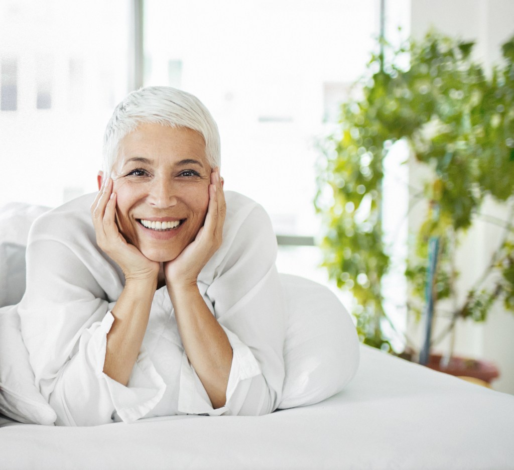 Gray haired woman relaxing with hands touching her face