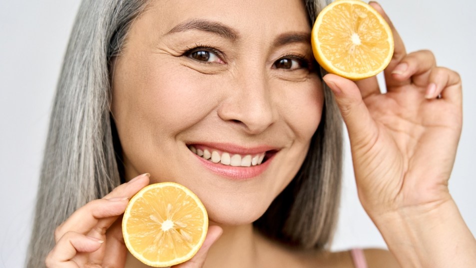 Closeup portrait of middle aged asian woman holding lemons and smiling