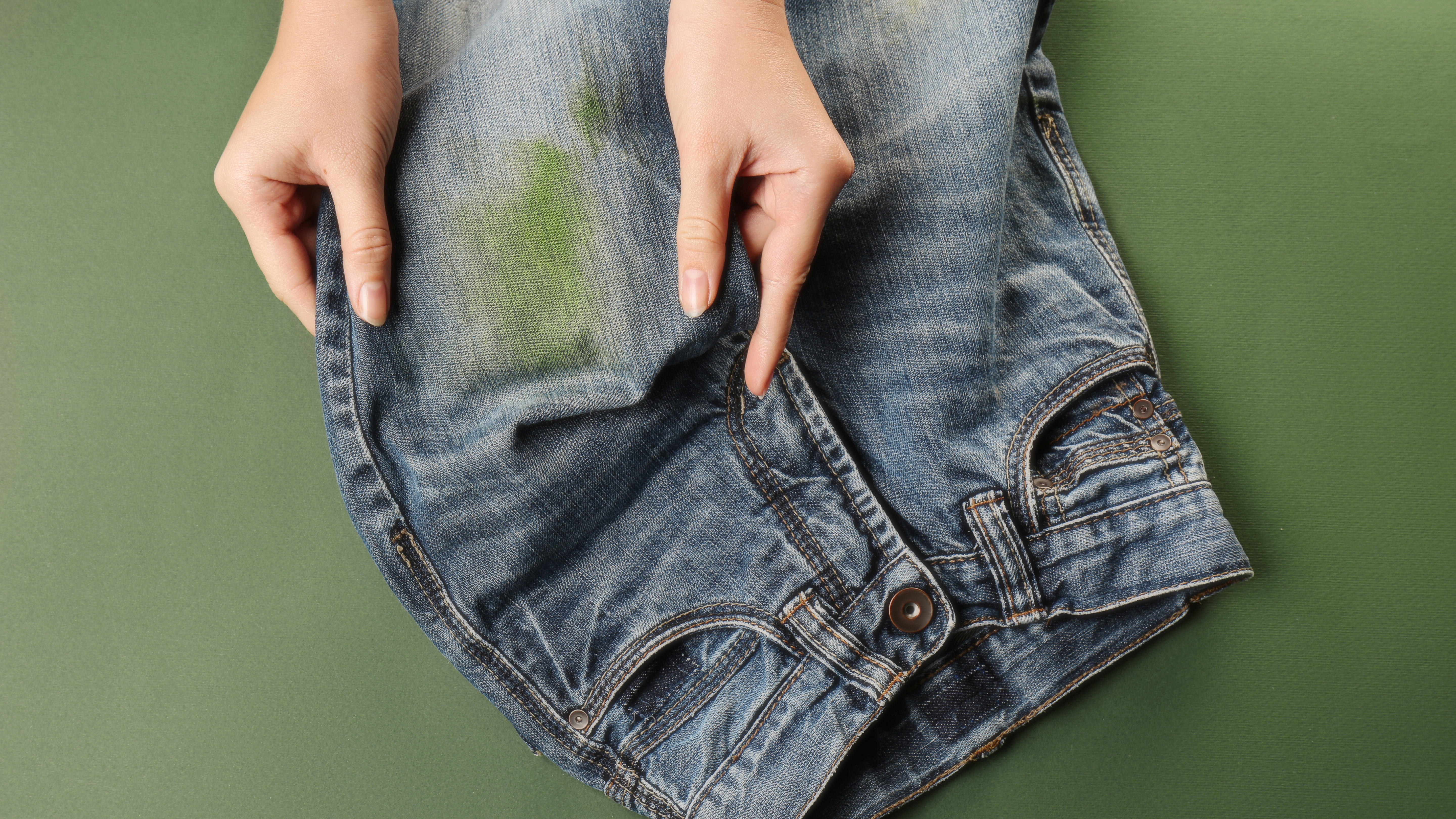 woman holding jeans with grass stains