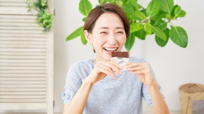 Asian woman eating chocolate bar at home