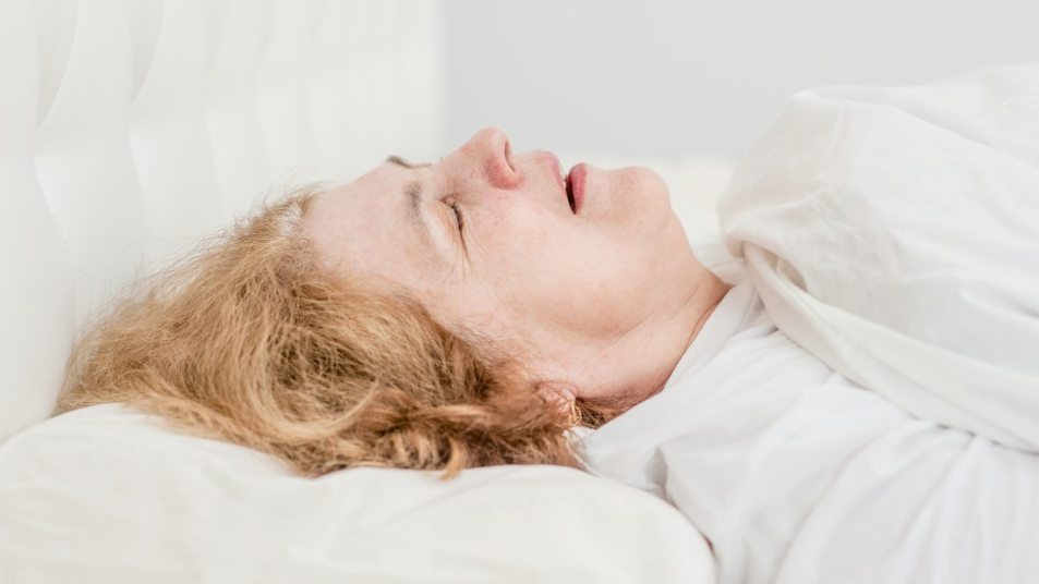 mature woman with light blond hair snoring in bed