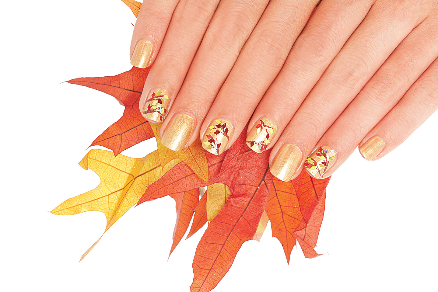 A woman holding leaves with her nails painted gold with a fall leaves manicure fall nail designs