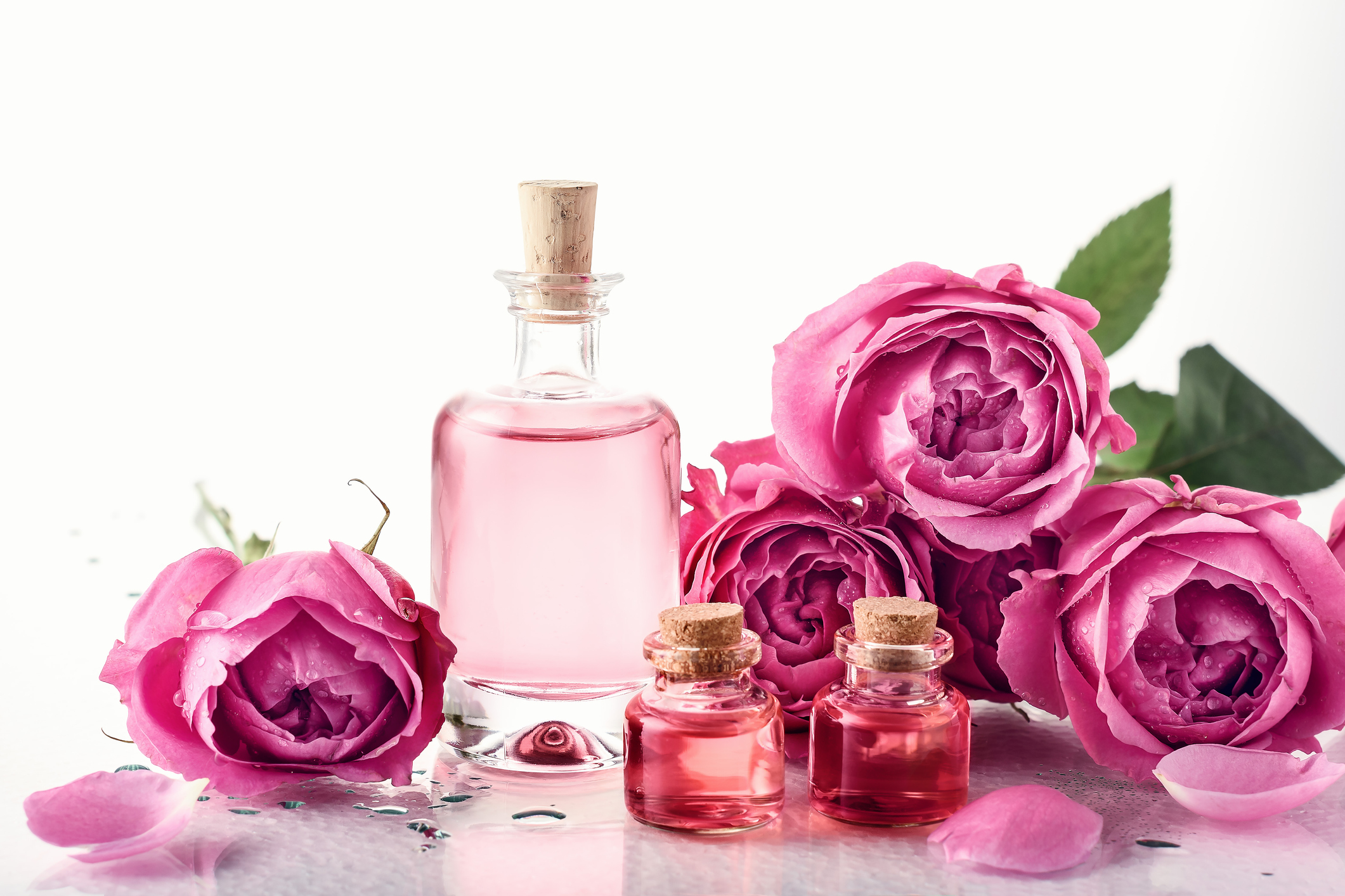 Bottles filled with rosewater and roses surrounding them to be used for a hand soak to end dry skin