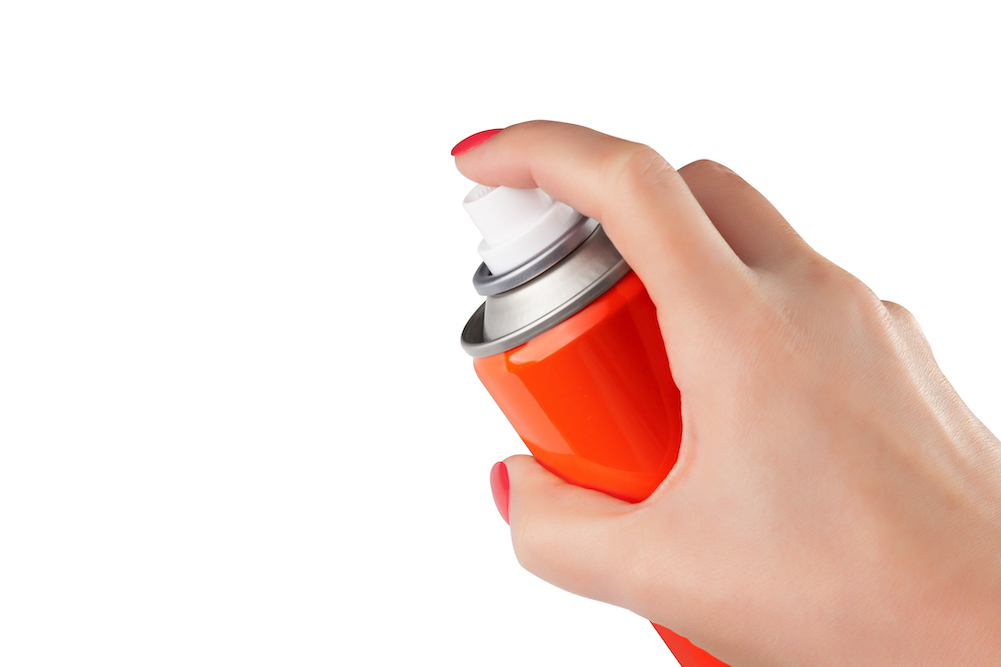 woman's hand holding red spray can to get rid of static on clothes