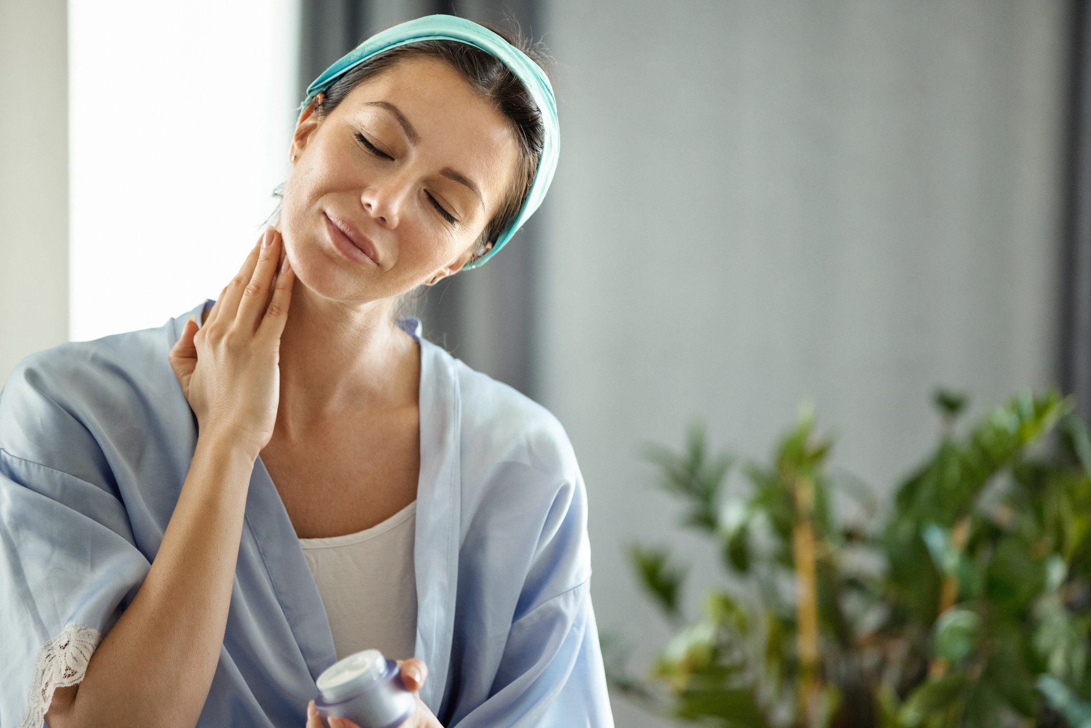 Woman applying moisturizer to neck to combat crepey neck