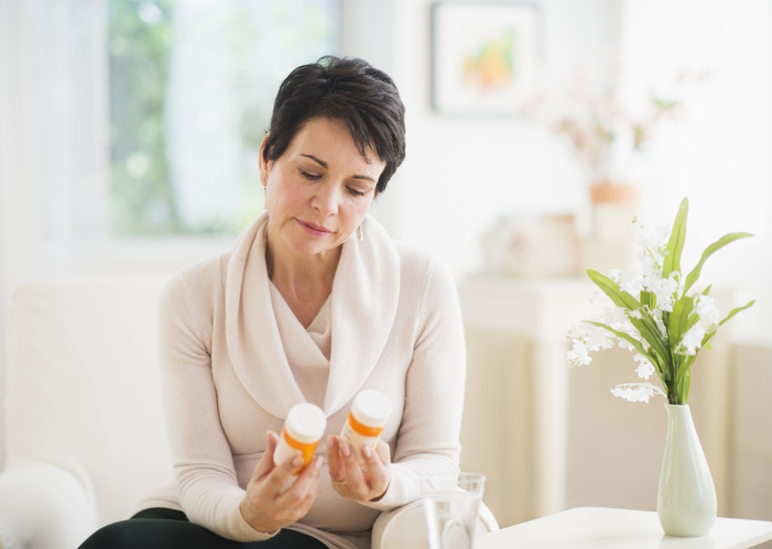 An older woman stares at two pill bottles after learning how to save on all your prescriptions