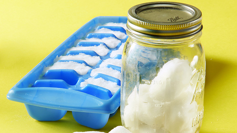 Homemade dishwashing detergent pods drying in an ice cube tray and stored in a lidded jar