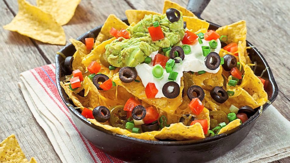 Nachos with Spicy Guacamole sit on a plate waiting to be eaten