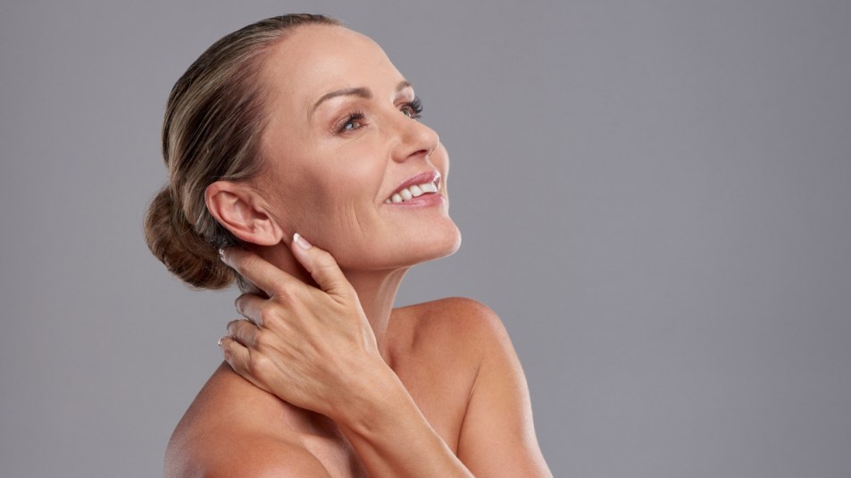 Mature woman feeling skin on neck and smiling
