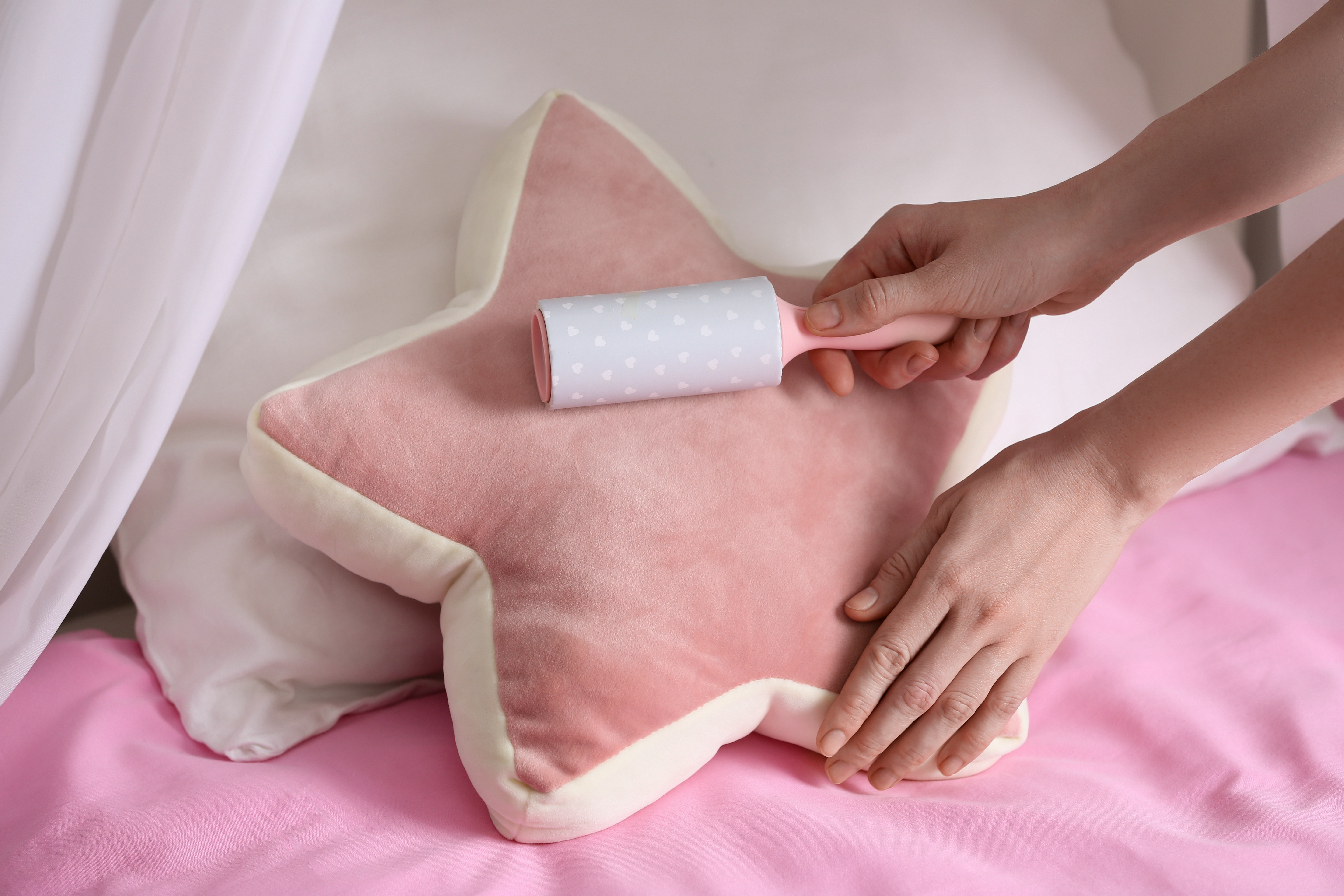 Woman cleaning pretty start shaped pillow with a lint roller 