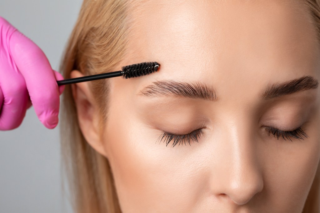 Woman giving herself brow lamination at home