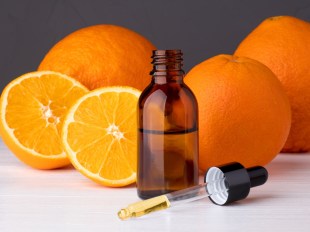 Bottle with essential oils, dropper with oil. Fresh oranges. (orange essential oil benefits.)