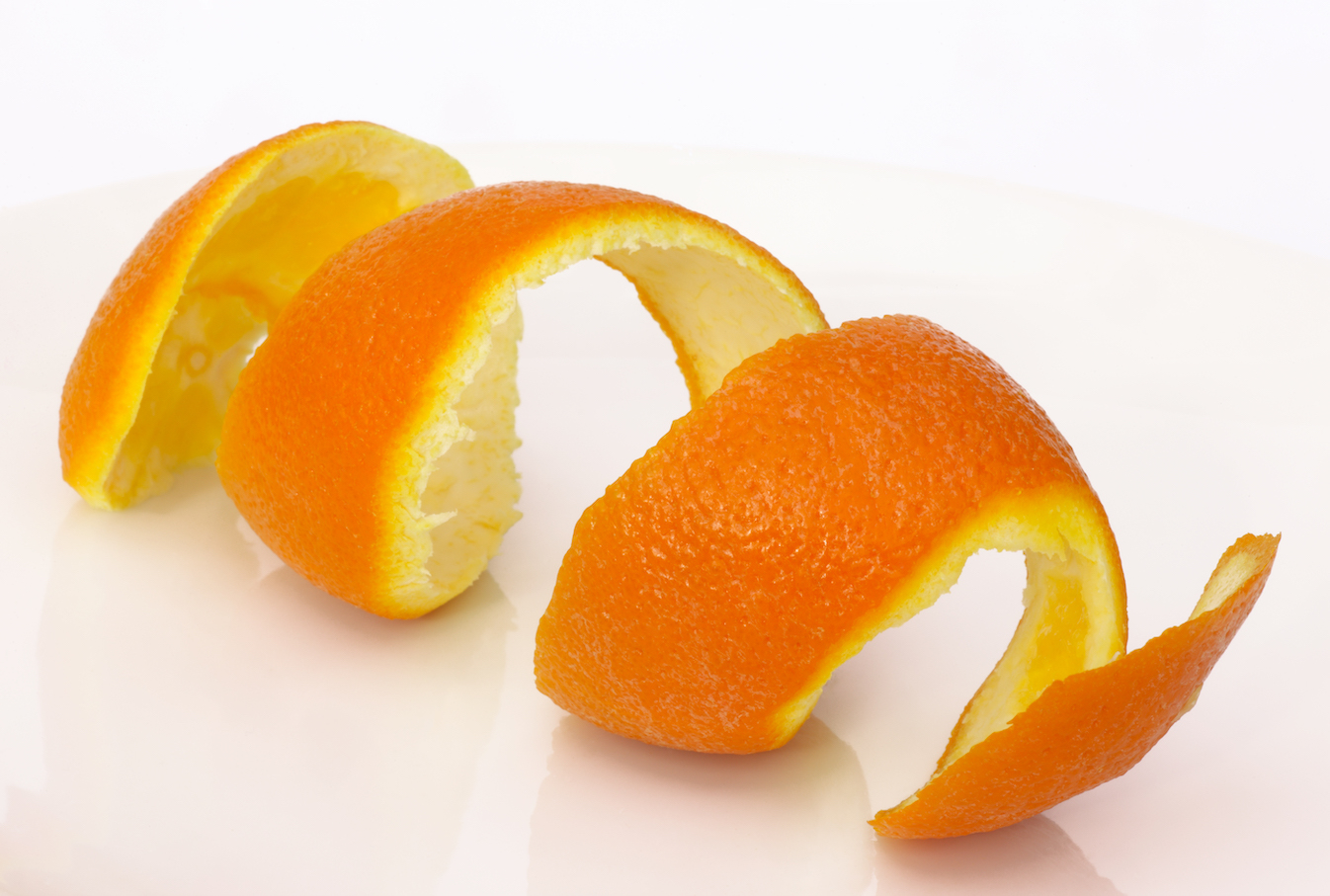 Coil of orange peel on a white background. for cleaning garbage disposal.