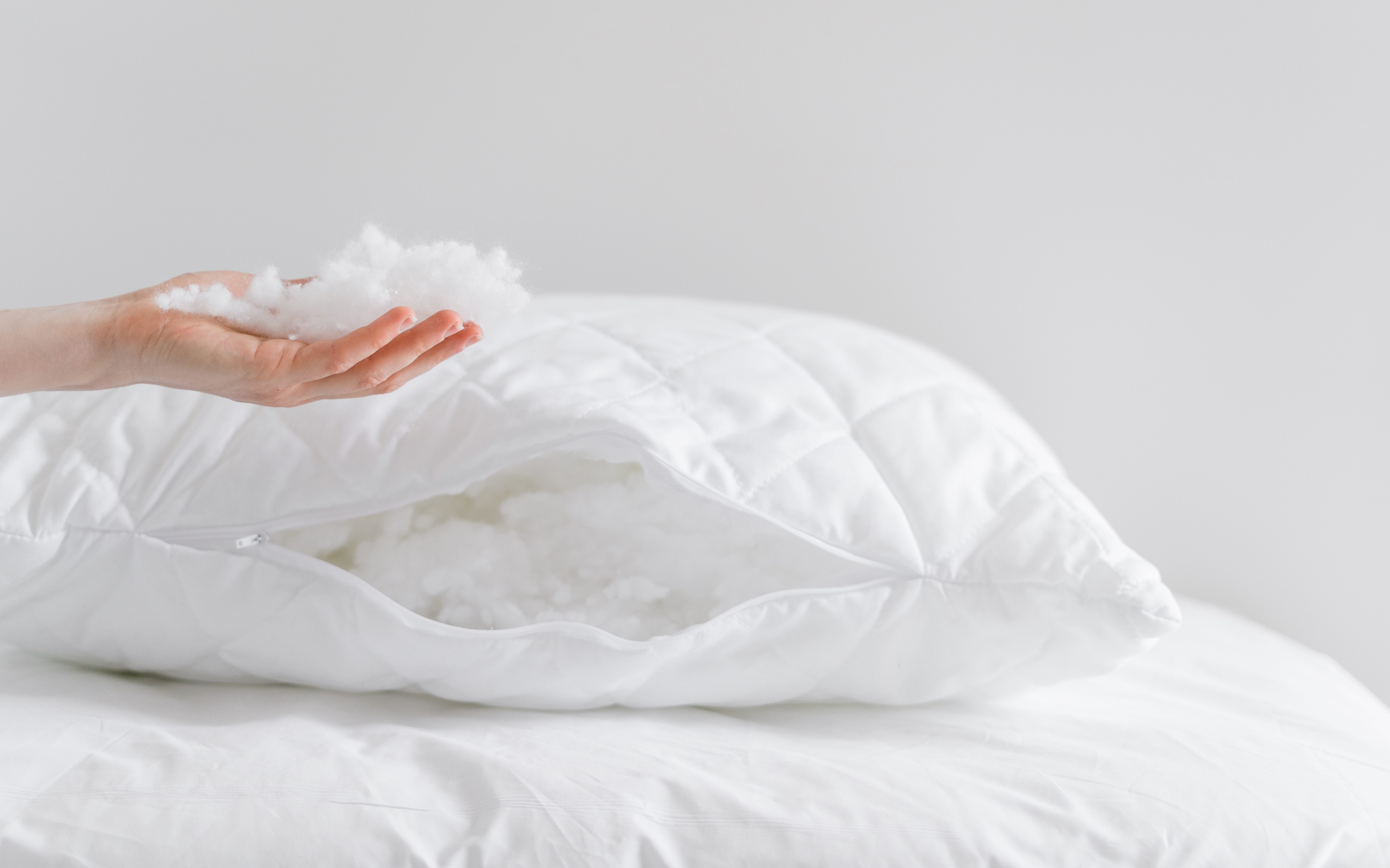 woman holding the inside of a polyester pillow next to a pillow