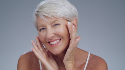 Mature woman smiling touching beautiful skin.