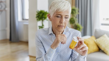 woman reading fosamax side effects on pill bottle