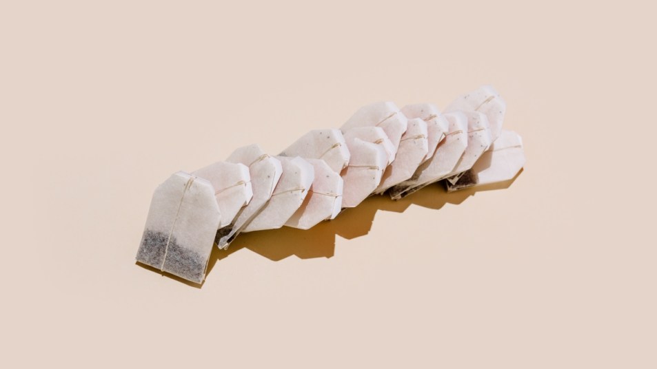 From above of paper tea bags arranged in row on beige background with empty space