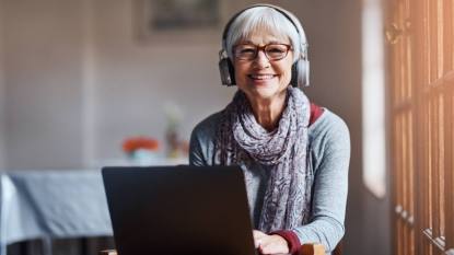 (Online transcription jobs for beginners) Shot of a senior woman using a laptop and headphones in a retirement home