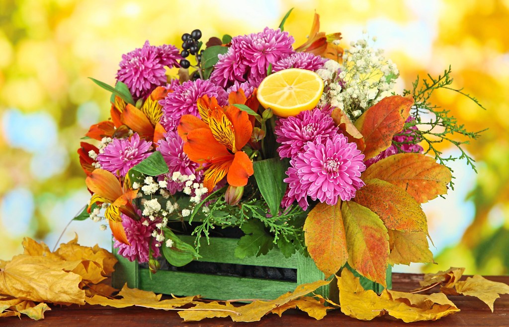 Table centerpiece ideas: Gorgeous autumn mix of flowers, fruit and leaves in a rustic green crate displayed on tabletop