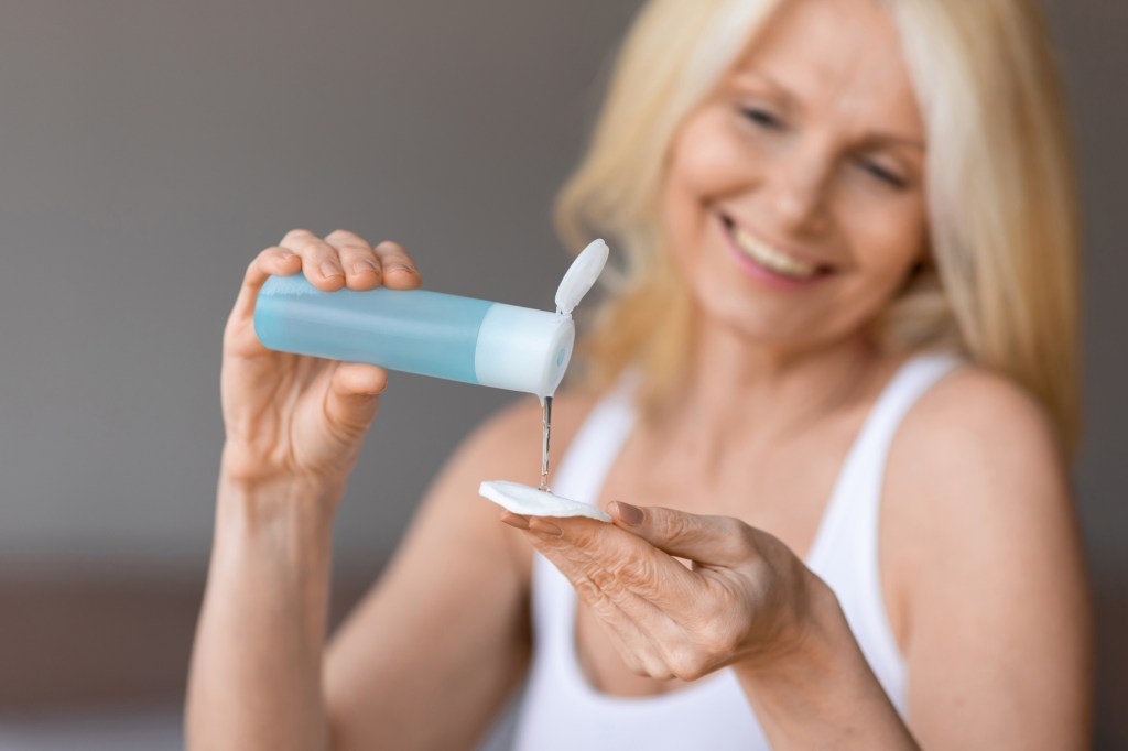 Mature woman using micellar water to double cleanse