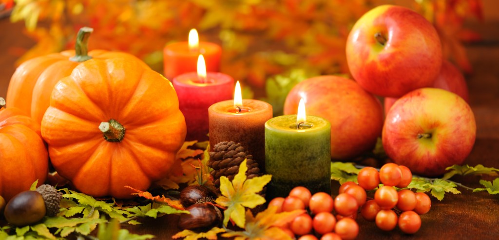 Table centerpiece ideas: candlescape centerpiece of autumn-hued votive candles and gourds on tabletop