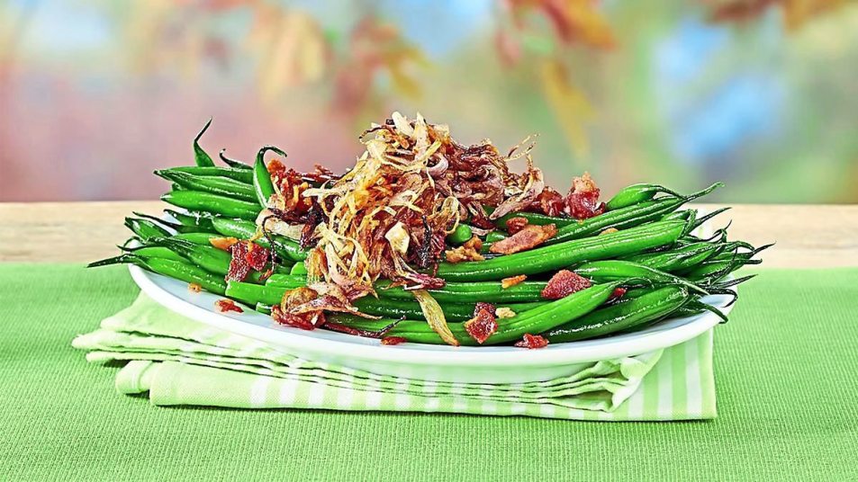 Garlicky Green Beans with Crispy Shallots sits on a green background (Side dishes for meatloaf)