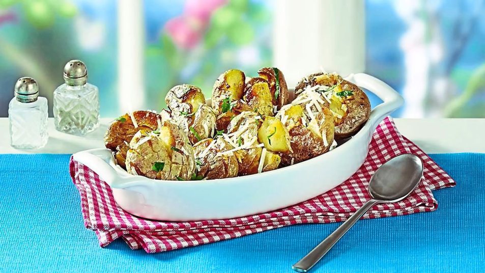 Garlic-Parmesan Smashed Potatoes sits on a white bowl (Side dishes for meatloaf)