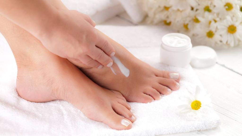 Woman putting lotion on her feet