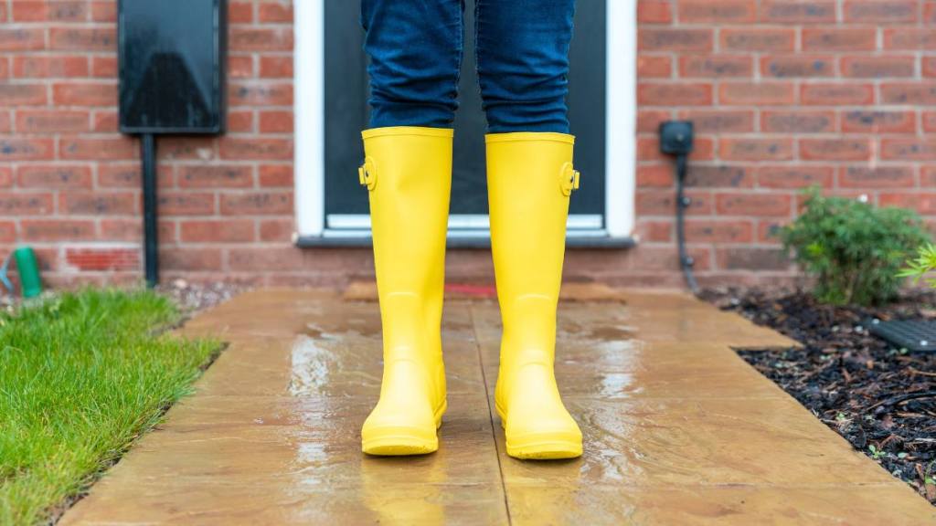 How to clean boots: Woman wearing rubber boot standing in back yard during rainy season