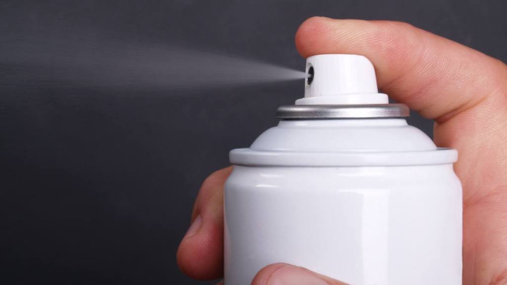 silence a squeaky door hinge: Macro of generic aerosol can spraying; copy space