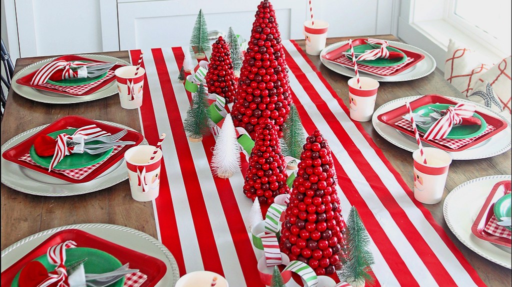 Christmas centerpiece ideas: Candy cane-themed centerpiece on wood dining table complete with red- and white-striped runner, cranberry-kissed Christmas trees, sisal trees and a paper chain garland