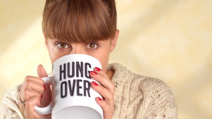 woman drinking coffee from a cup that reads 'hungover" best foods for hangover