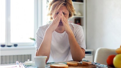 woman at a table eating bread and looking tired: does gluten make you tired?