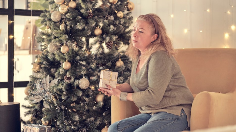 Woman looking stressed and sitting by Christmas tree