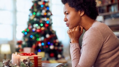 Contemplative woman sitting in profile by Christmas tree