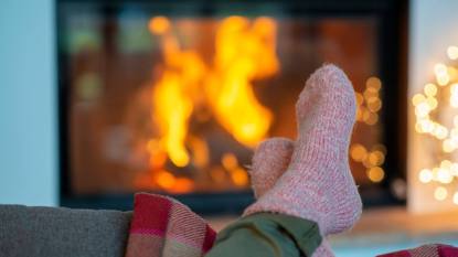 How to keep your feet warm: Legs of young woman wearing socks relaxing against fireplace at home