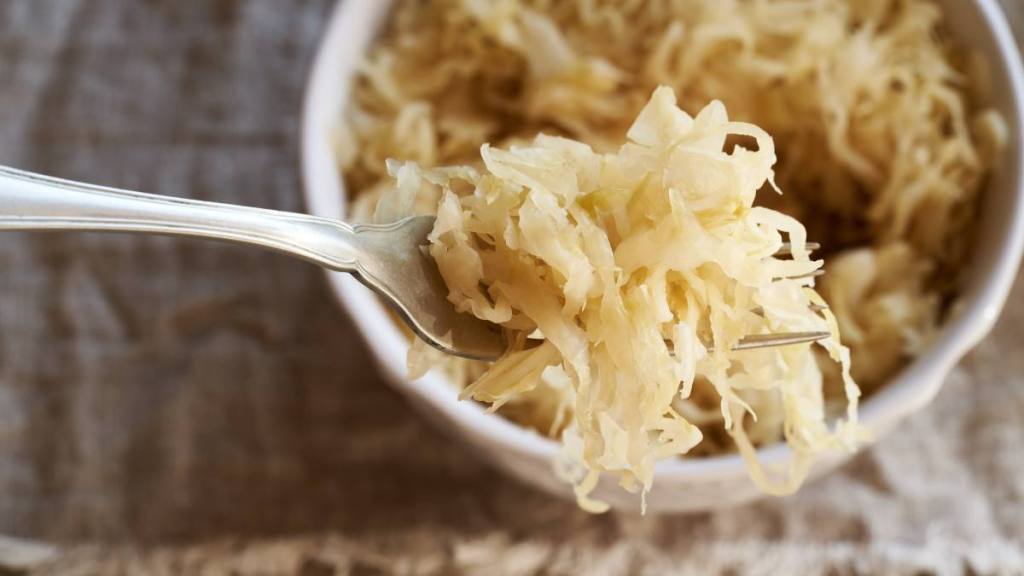 The best foods to eat for gut health: Fermented cabbage or sauerkraut on a metal fork