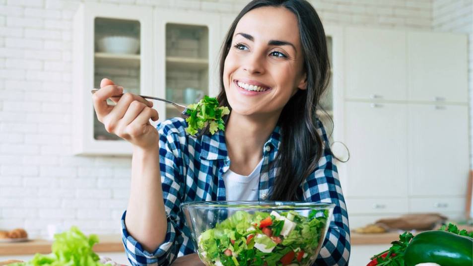 How to eat more vegetables: Healthy lifestyle. Good life. Organic food. Vegetables. Close up portrait of happy cute beautiful young woman while she try tasty vegan salad in the kitchen at home.