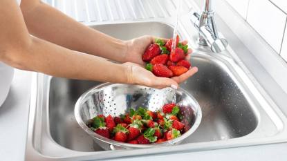 How to Clean Fruit: Woman is washing strawberry in the kitchen.