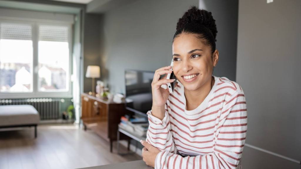 Part time online jobs: Young African-American woman smiling while talking on the phone with close friend