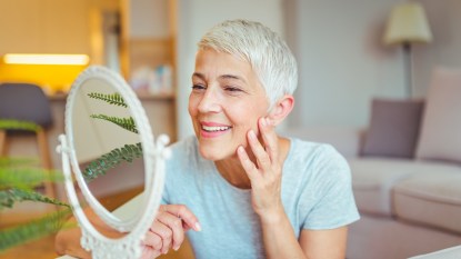 mature woman looking at skin in mirror