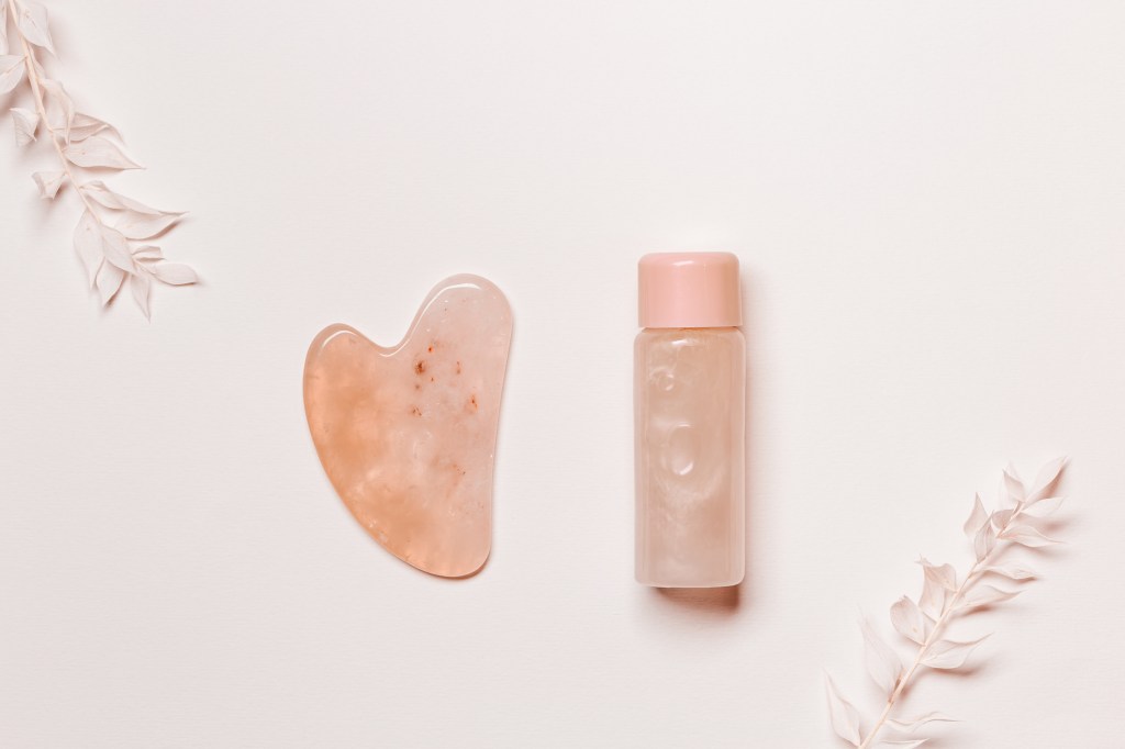Overshot of gua sha next to bottle of face oil