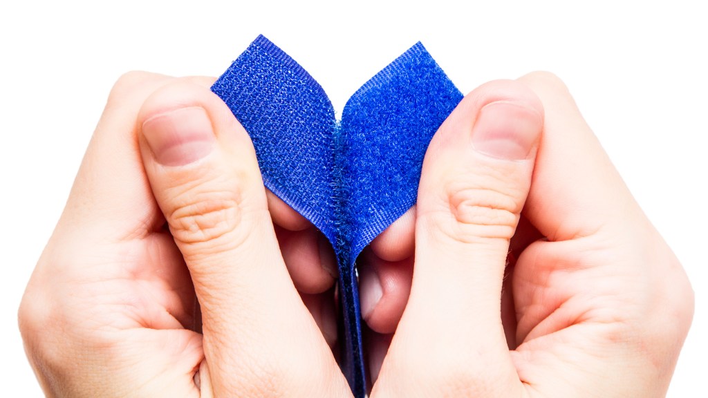 Blue Velcro strips being peeled apart by hands on a white background