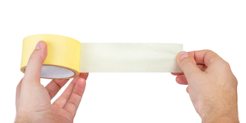 Clear packing tape being unraveled from roll by man's hands on white background