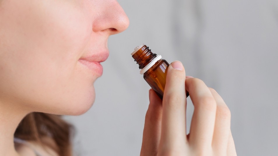 Close-up of woman sniffing bottle of essential oil