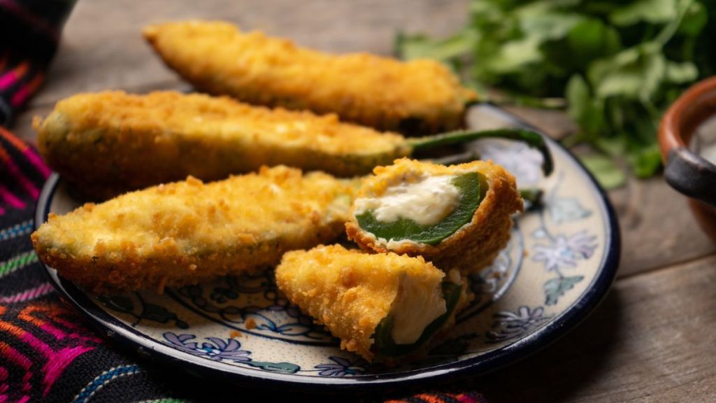 Traditional mexican jalapeno poppers stuffed with cheese and breaded on wooden background