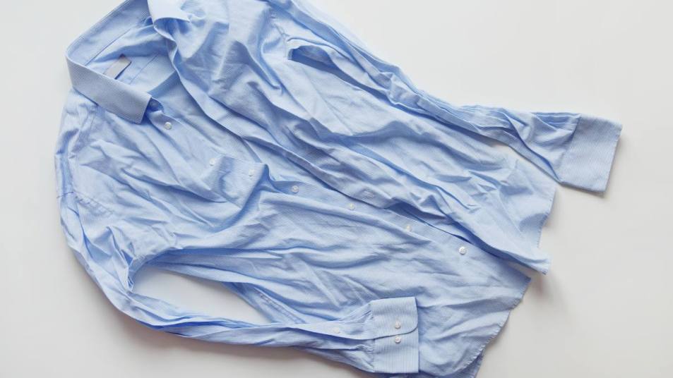 How to get wrinkles out of clothes: Blue cotton wrinkled and rumpled shirt on white. Washed shirt after tumble dryer.