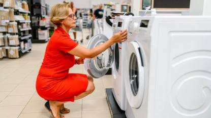 best time to buy appliances: Mature woman in a store chooses a washing machine.