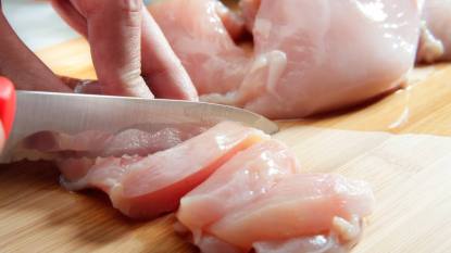 How to prevent food poisoning: hand cutting raw chicken breast. Selective focus