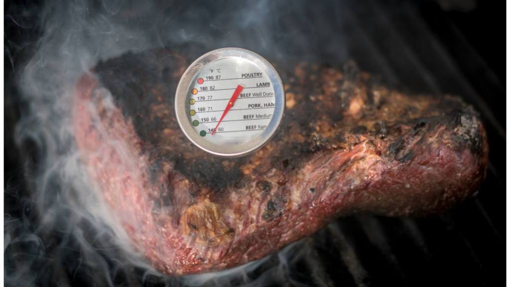 How to prevent food poisoning: Isolated close up of a delicious beef Picanha meat loaf roasting on a hot grill with a temperature gauge